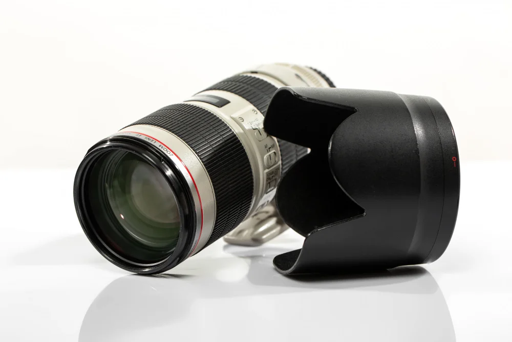Telephoto lens beside its black lens hood on a white surface