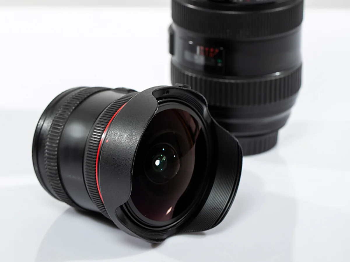 Two camera lenses on a white studio surface